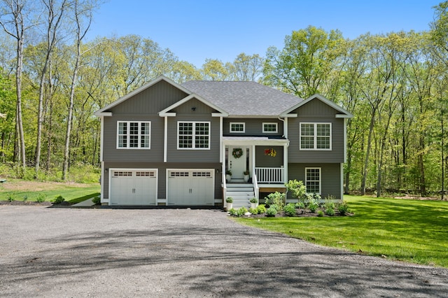 bi-level home with a front lawn, an attached garage, driveway, and a shingled roof