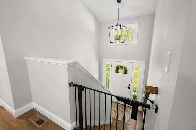 stairs with wood finished floors, baseboards, visible vents, an inviting chandelier, and a high ceiling