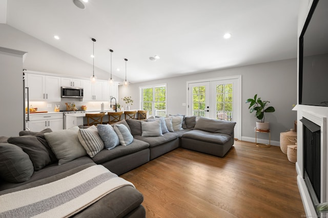 living area featuring wood finished floors, baseboards, a fireplace, recessed lighting, and french doors