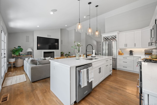 kitchen featuring visible vents, light wood-style flooring, a sink, stainless steel appliances, and open floor plan