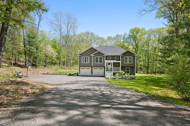 bi-level home with a front yard, a garage, and aphalt driveway