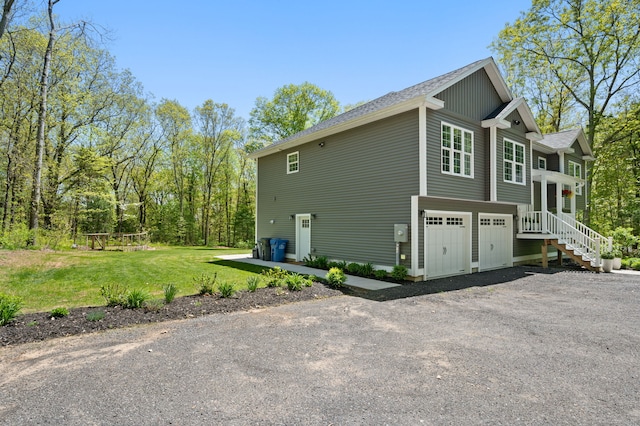 view of side of home with a lawn, an attached garage, and driveway