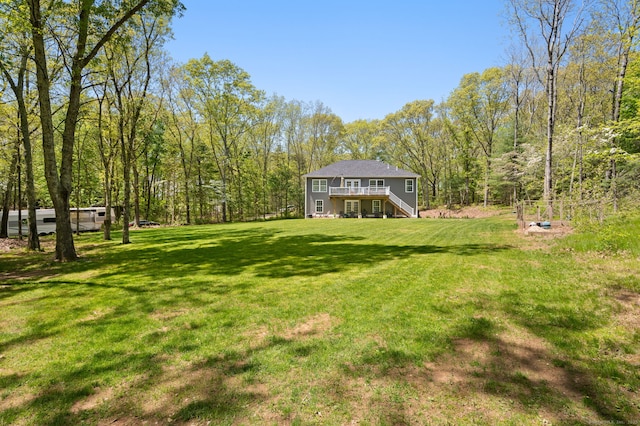 view of yard featuring stairway, a forest view, and a deck