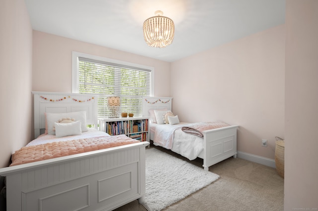 carpeted bedroom with a notable chandelier and baseboards