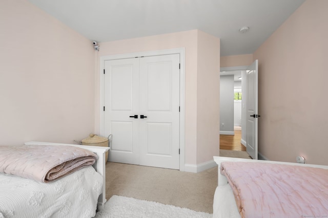 bedroom featuring a closet, light colored carpet, and baseboards