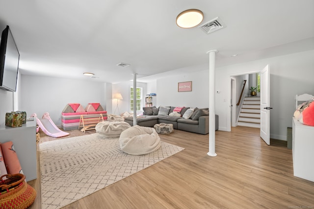 living area featuring light wood-type flooring, visible vents, and stairs