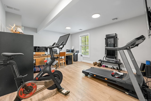 workout room with wood finished floors, visible vents, and baseboards