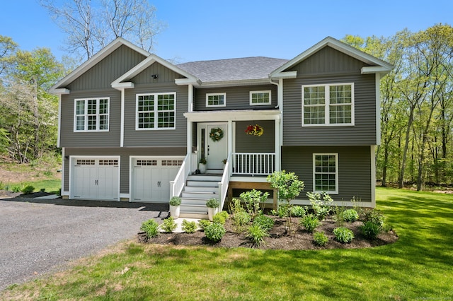 raised ranch with driveway, an attached garage, a front lawn, and a shingled roof