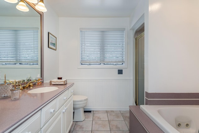 full bathroom with a wainscoted wall, toilet, vanity, a jetted tub, and tile patterned floors