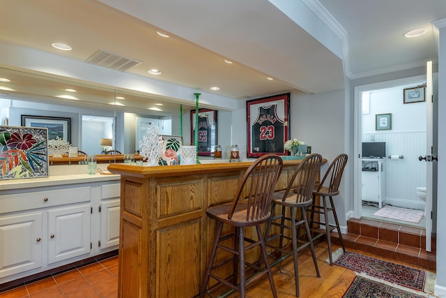 bar with a wainscoted wall, crown molding, indoor bar, recessed lighting, and visible vents