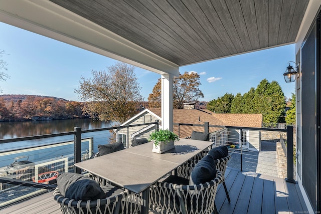 wooden terrace featuring outdoor dining area and a water view