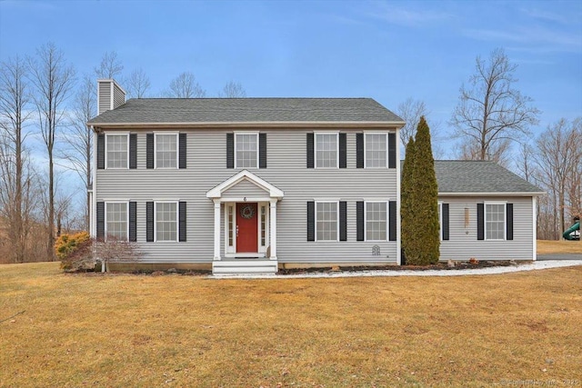 colonial-style house featuring a front yard and a chimney