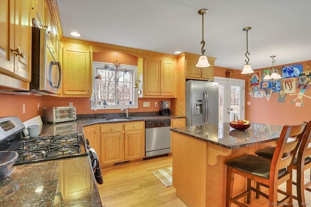 kitchen featuring a kitchen island, a toaster, a sink, appliances with stainless steel finishes, and a kitchen bar