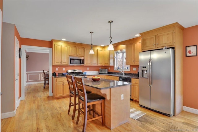 kitchen with a breakfast bar area, a kitchen island, light wood-style flooring, appliances with stainless steel finishes, and decorative light fixtures