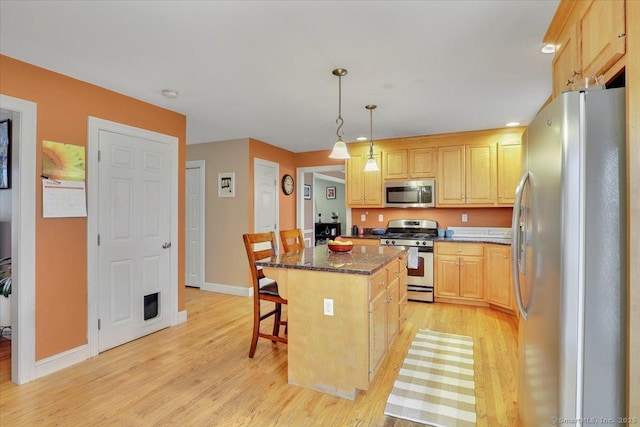 kitchen with a kitchen island, light brown cabinetry, a breakfast bar area, light wood-style floors, and stainless steel appliances