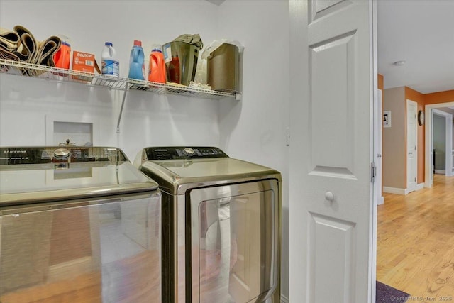 laundry area featuring baseboards, independent washer and dryer, light wood-style flooring, and laundry area