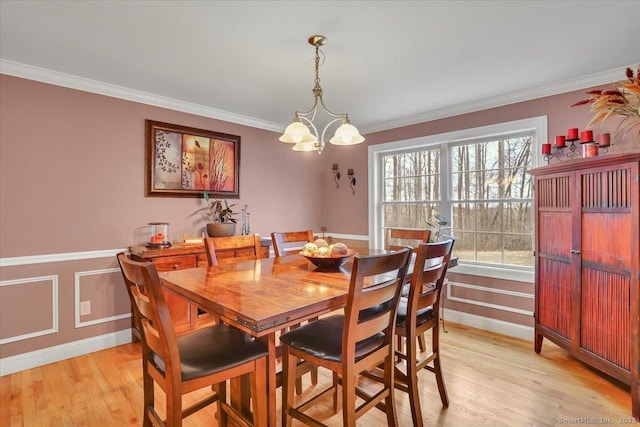 dining area featuring baseboards, light wood-type flooring, an inviting chandelier, and ornamental molding