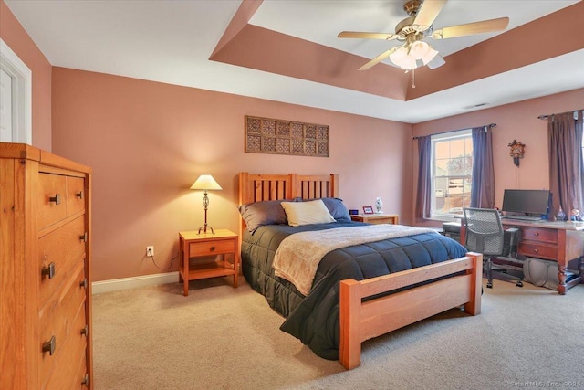 carpeted bedroom with baseboards, a raised ceiling, visible vents, and a ceiling fan