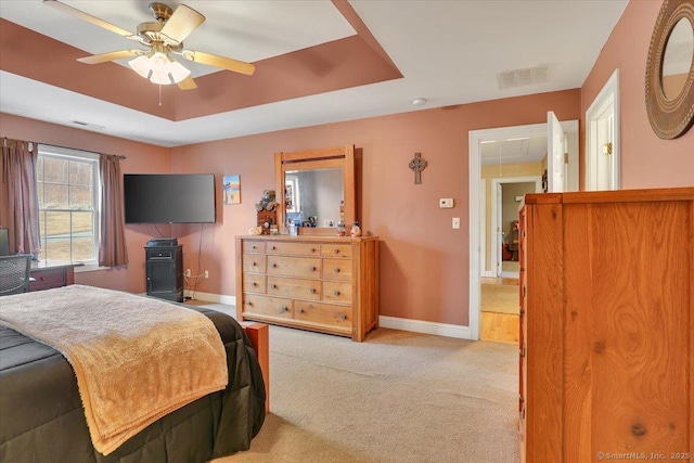 carpeted bedroom featuring attic access, baseboards, visible vents, and a raised ceiling