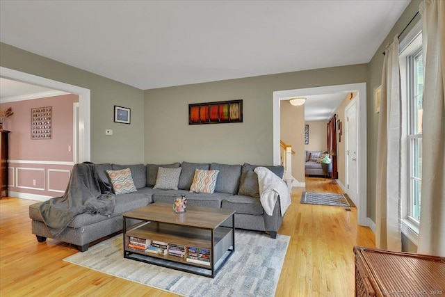 living area featuring stairs, a decorative wall, and light wood-type flooring