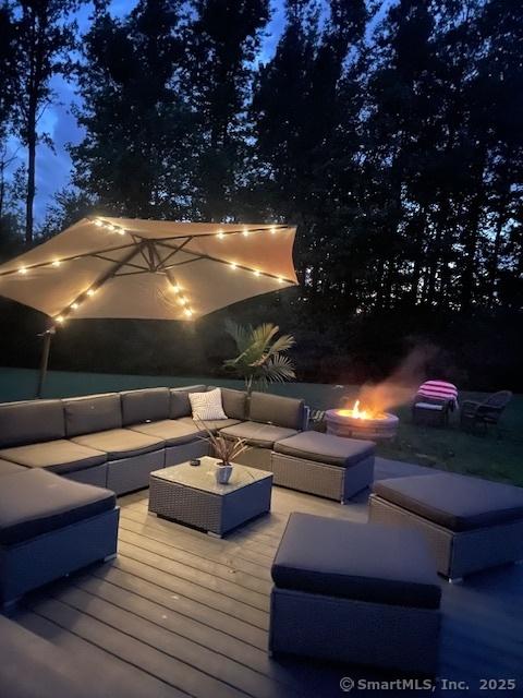 wooden terrace with an outdoor living space with a fire pit