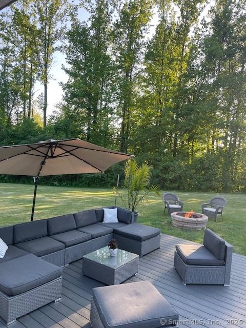 wooden terrace featuring a yard and an outdoor living space with a fire pit