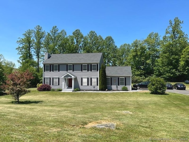 colonial-style house with a chimney and a front lawn