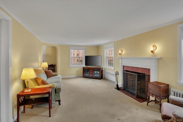 carpeted living room with crown molding, a fireplace, arched walkways, and baseboards