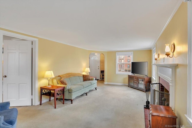 living area featuring a fireplace, carpet, arched walkways, and ornamental molding