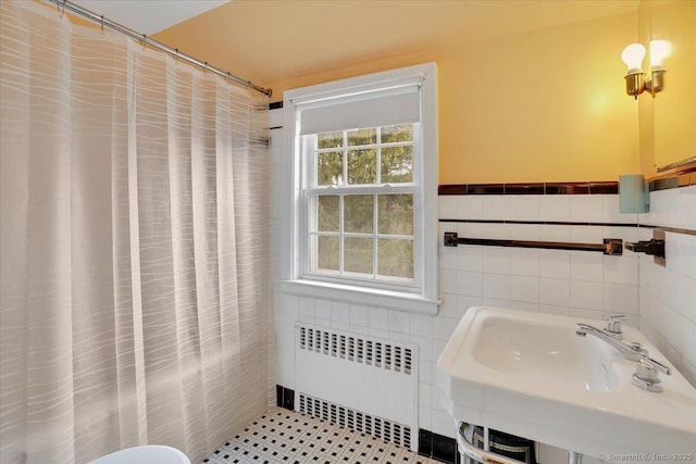 bathroom featuring radiator, a wainscoted wall, a sink, curtained shower, and tile walls