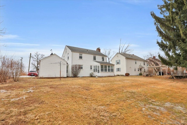 rear view of house featuring a lawn, a chimney, and a sunroom