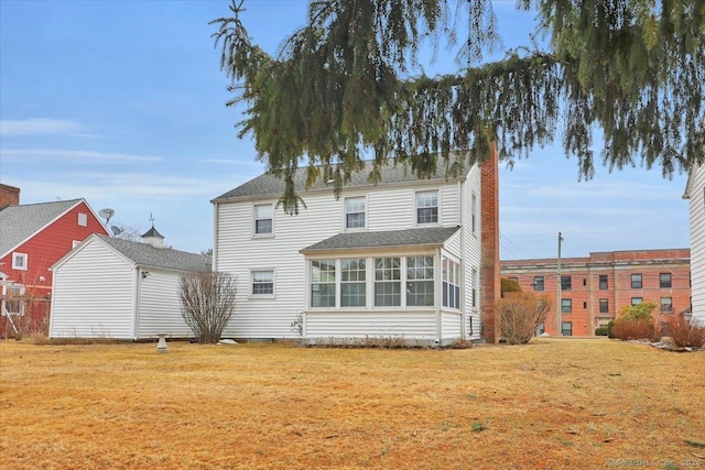 back of house featuring a lawn and a sunroom