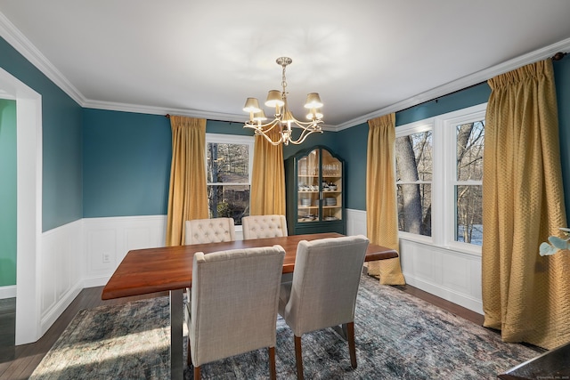 dining area featuring an inviting chandelier, crown molding, wood finished floors, and wainscoting