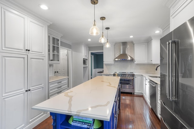 kitchen with dark wood-style flooring, a sink, high quality appliances, white cabinets, and wall chimney exhaust hood