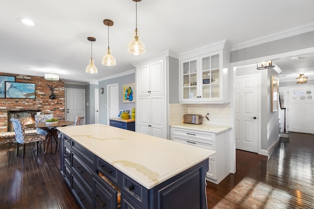 kitchen with blue cabinets, dark wood-style flooring, white cabinetry, ornamental molding, and glass insert cabinets