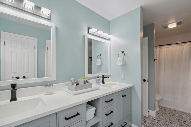 bathroom with visible vents, a sink, toilet, and double vanity