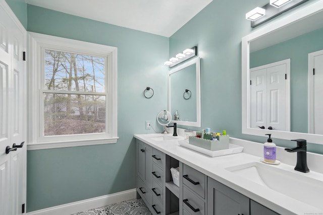 full bathroom featuring double vanity, baseboards, and a sink