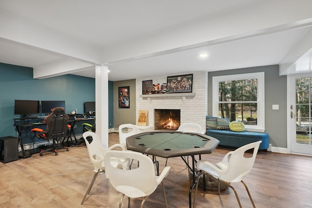 playroom featuring beamed ceiling, a fireplace, wood finished floors, and baseboards