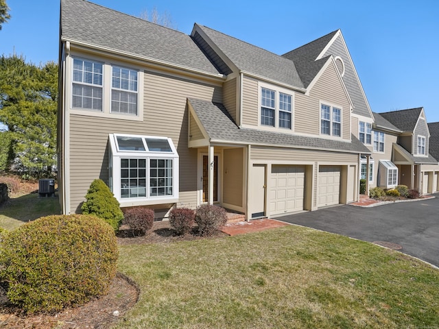 view of front of property featuring an attached garage, a front yard, driveway, and roof with shingles