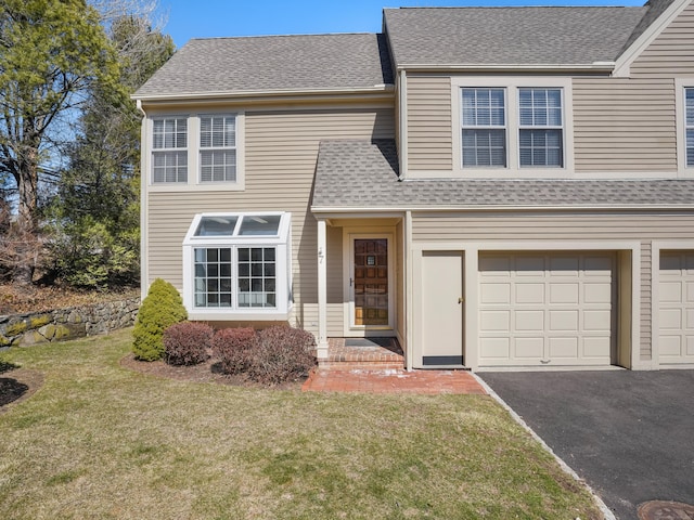 traditional-style home featuring aphalt driveway, a front lawn, roof with shingles, and an attached garage