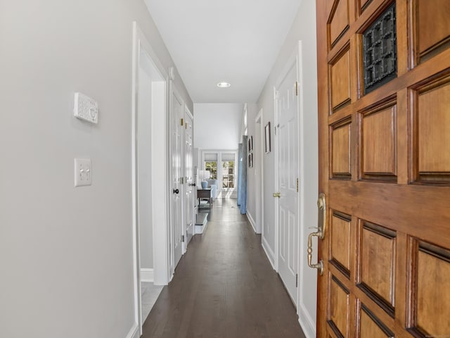 corridor featuring dark wood-type flooring and baseboards