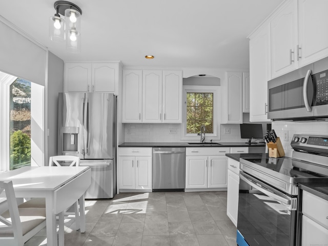 kitchen with dark countertops, decorative backsplash, appliances with stainless steel finishes, and a sink