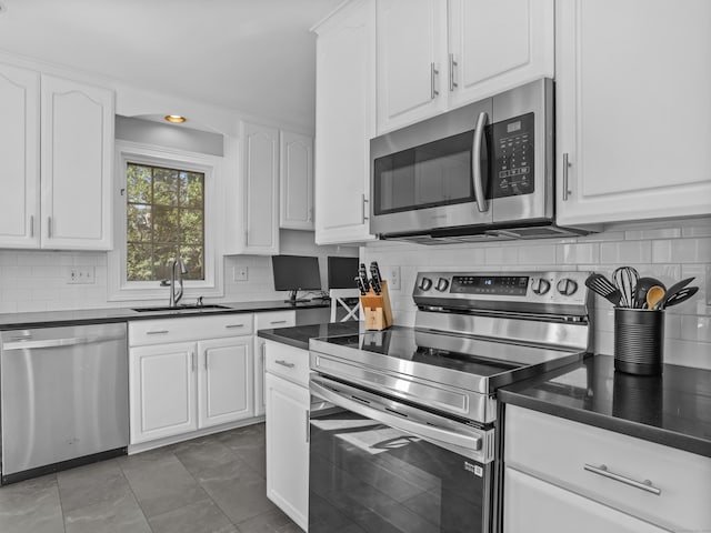 kitchen featuring a sink, stainless steel appliances, dark countertops, and white cabinets