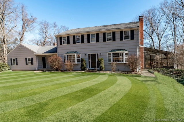 back of property with a lawn and a chimney