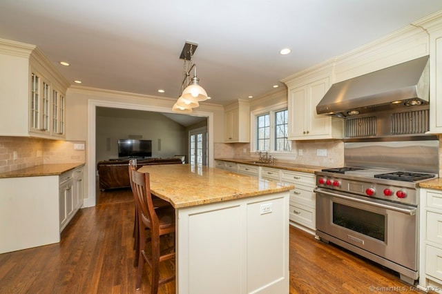 kitchen with a sink, light stone counters, dark wood finished floors, premium range, and wall chimney exhaust hood