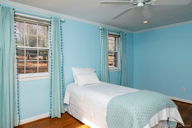 bedroom featuring multiple windows, baseboards, wood finished floors, and crown molding