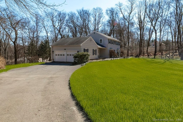 view of front of property with a front yard, an attached garage, and driveway