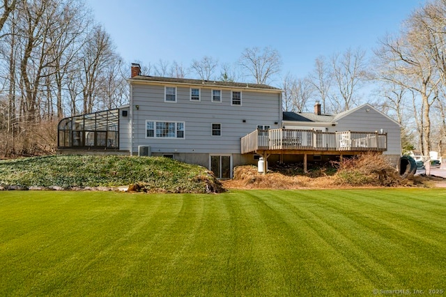 rear view of house with central AC unit, a lawn, a chimney, and a deck