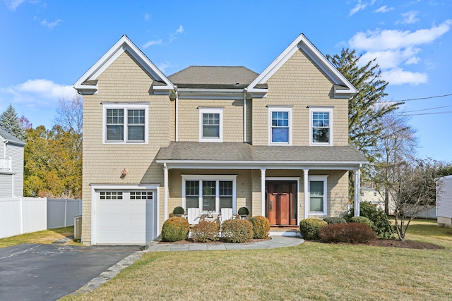 view of front of house featuring a front yard, fence, a porch, a shingled roof, and aphalt driveway