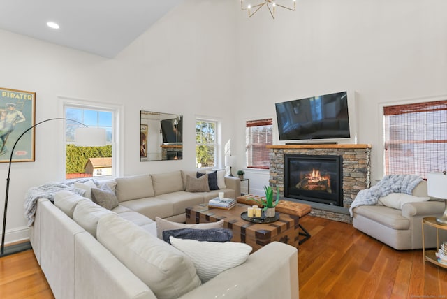 living area with baseboards, recessed lighting, a fireplace, wood finished floors, and high vaulted ceiling